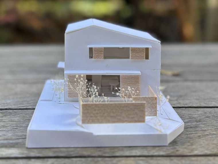 “ギングロ”のガルバリウム鋼板を外壁に採用し、戸袋や玄関扉の木部が心地よいアクセントとなる外観に仕上げました。<br />
建物を包み込むように庭の緑を計画的に配置することで、室内外のどちらからも「緑のある暮らし」を愉しめます。